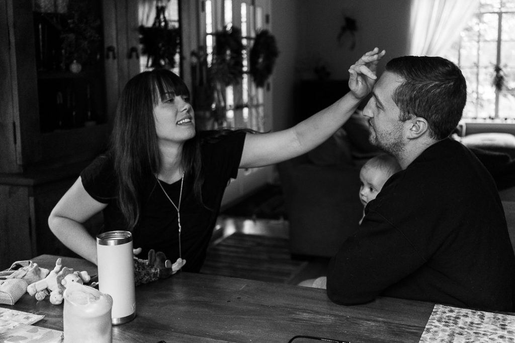 Fotografia documentaria di famiglia La madre accareza il padre mentre sono a tavola