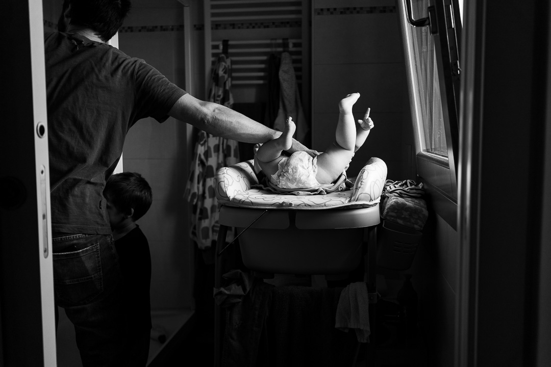 Fotografia documentaria di famiglia il padre sta cambiambo il pannolino