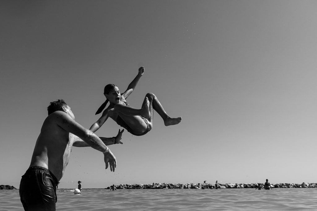 Fotografia documentaria di famiglia il padre fa fare un tufo in mare alla figlia