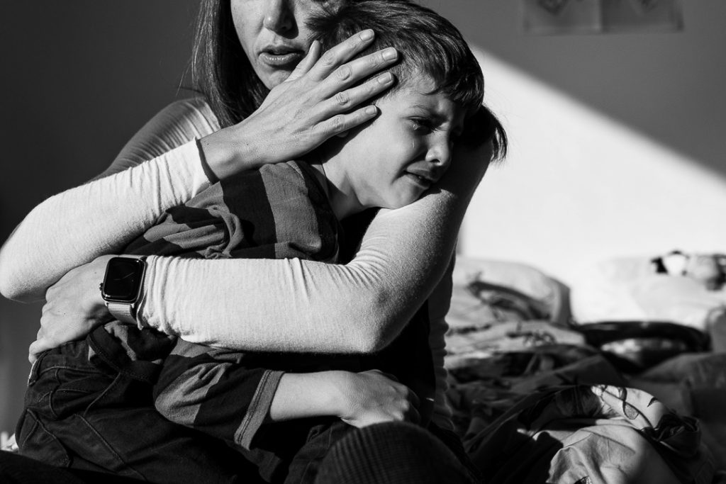 Fotografia documentaria di famiglia la madre cosola il figlio che piange
